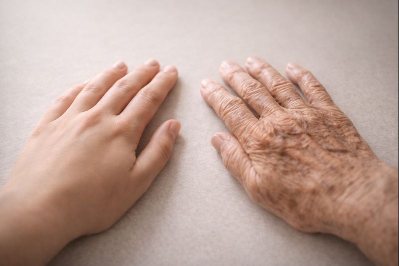 Deux mains féminines côte à côte, l’une jeune et lisse, l’autre très âgée et marquée, symbolisant la dignité partagée entre générations.