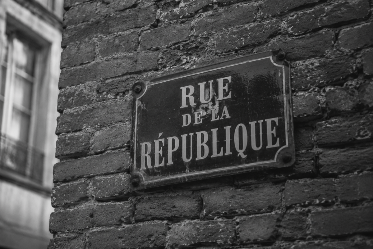Une plaque signalétique ancienne fixée sur un mur de briques texturé.