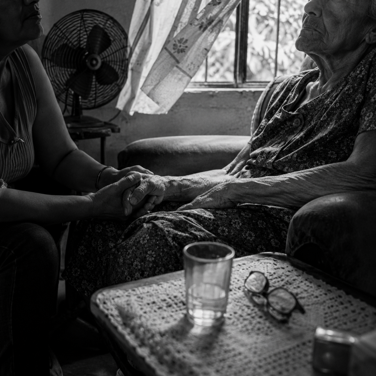 Une proche tient la main d’une personne âgée malade dans son domicile en Amérique latine.