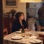 Un frère et une sœur restent autour de la table familiale après un repas, manifestement en désaccord.