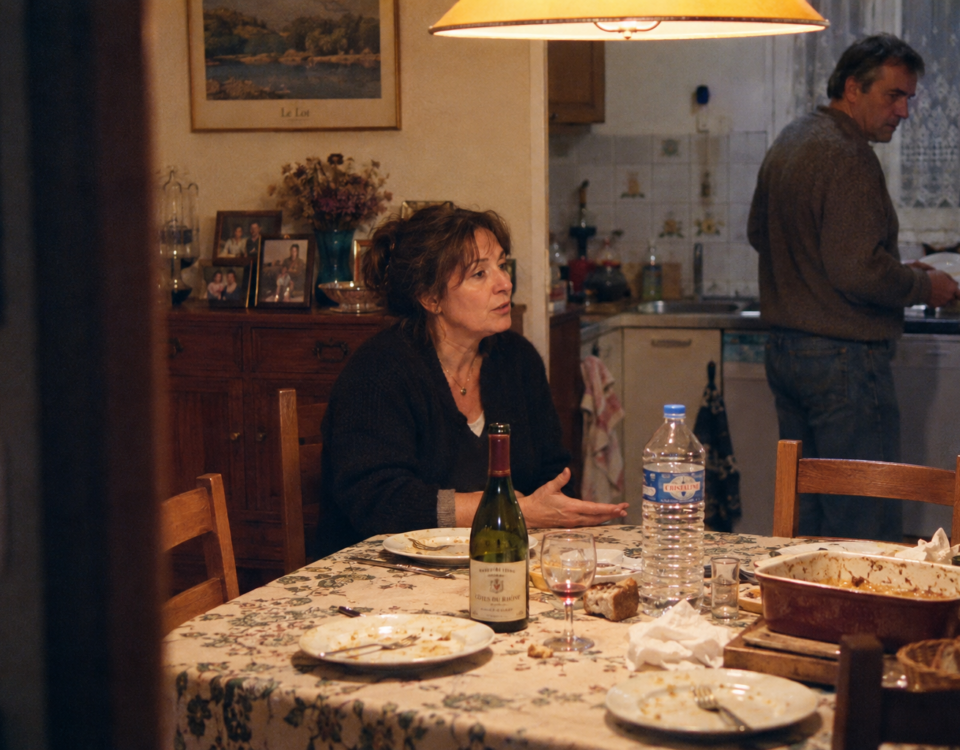 Un frère et une sœur restent autour de la table familiale après un repas, manifestement en désaccord.