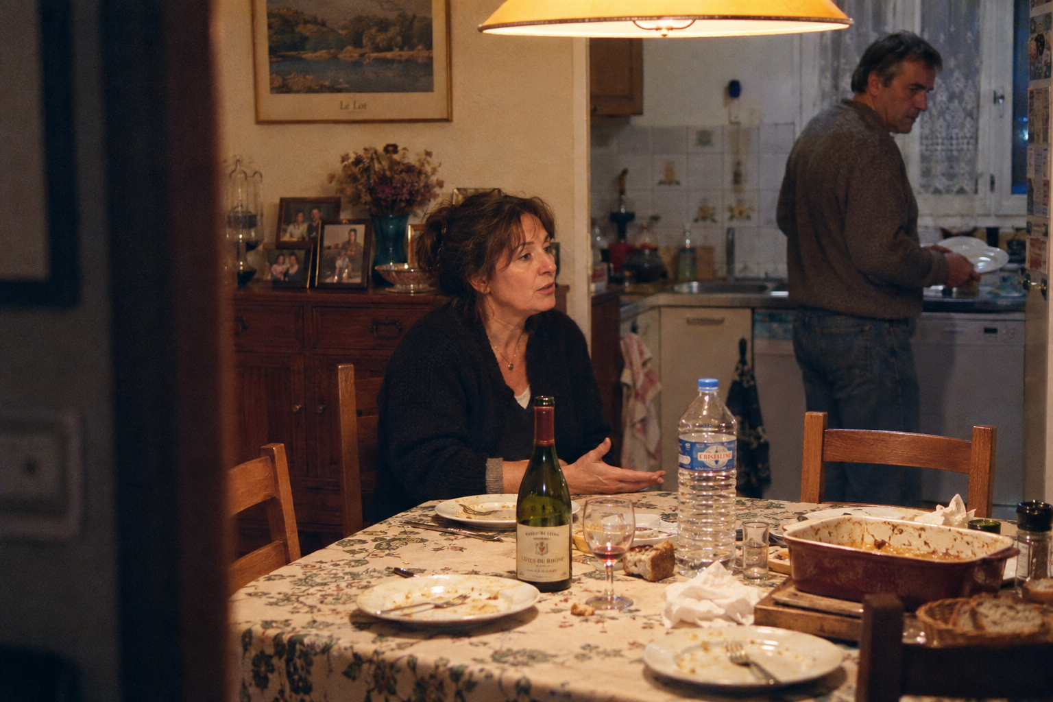 Un frère et une sœur restent autour de la table familiale après un repas, manifestement en désaccord.